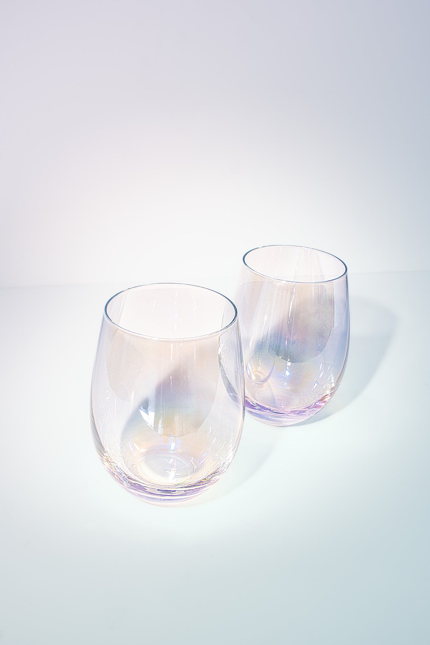 Two iridescent stemless glasses, radiating light