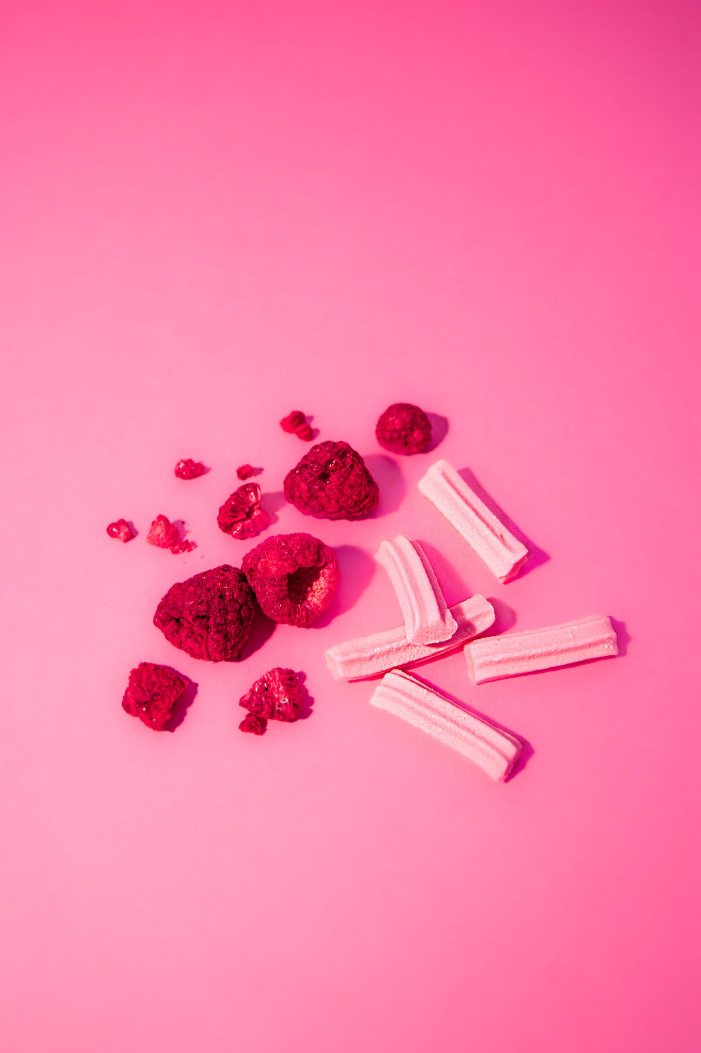 Raspberries and musk lollies on a pink background