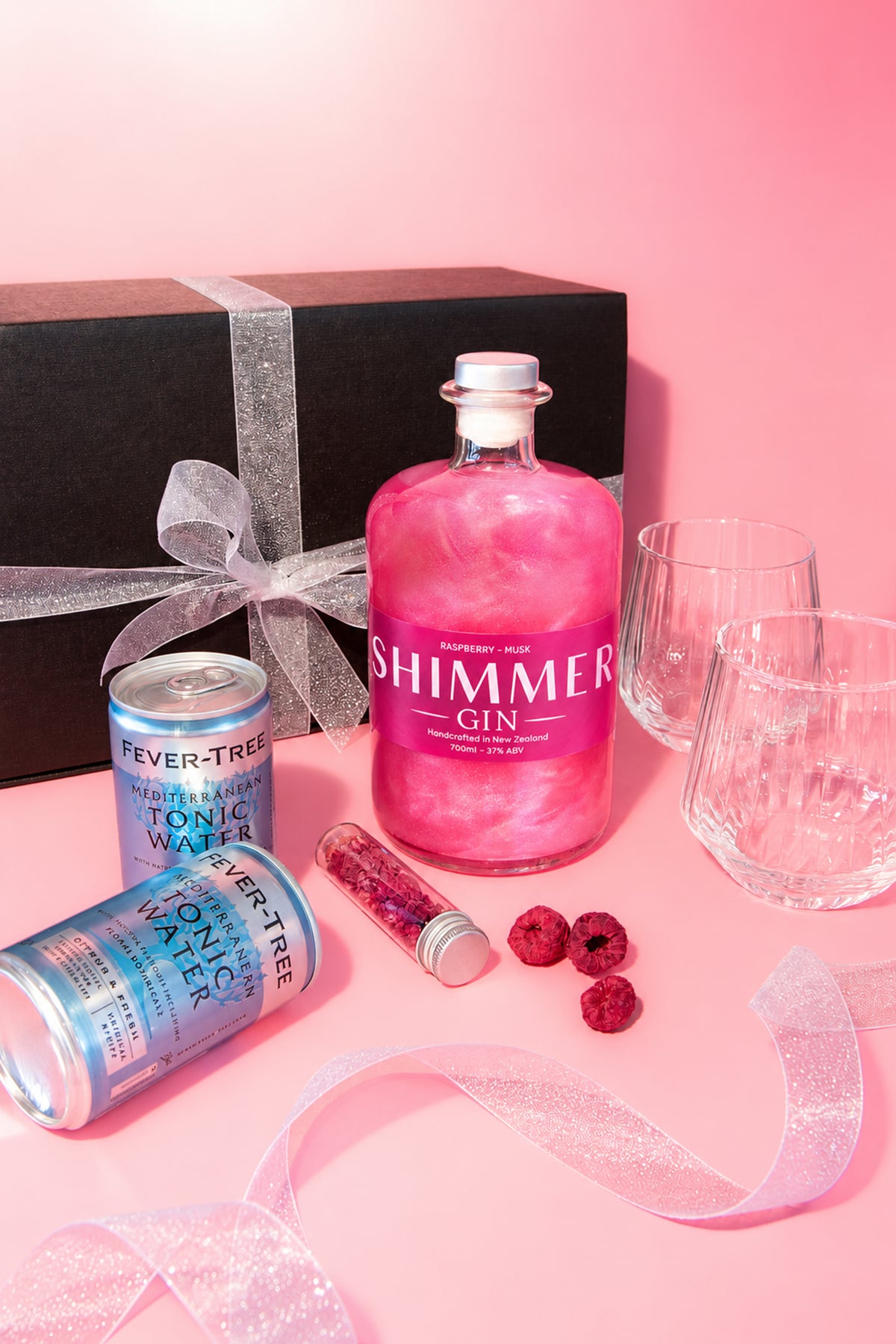 SIP Distilling Co. Pink Shimmer Gin Gift Box with raspberry gin, tonic water, glasses and raspberry garnish on a pink background