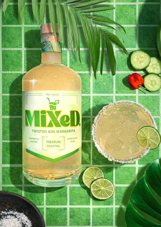 Bottle of MIXED Twisted Gin Margarita premixed cocktail beside a salted margarita glass with lime slices on a green tiled background.