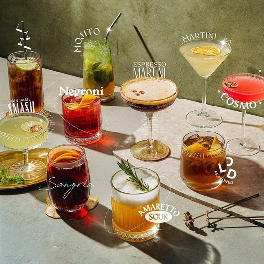 A styled overhead photo of a marble table displaying an assortment of classic cocktails in different glassware.