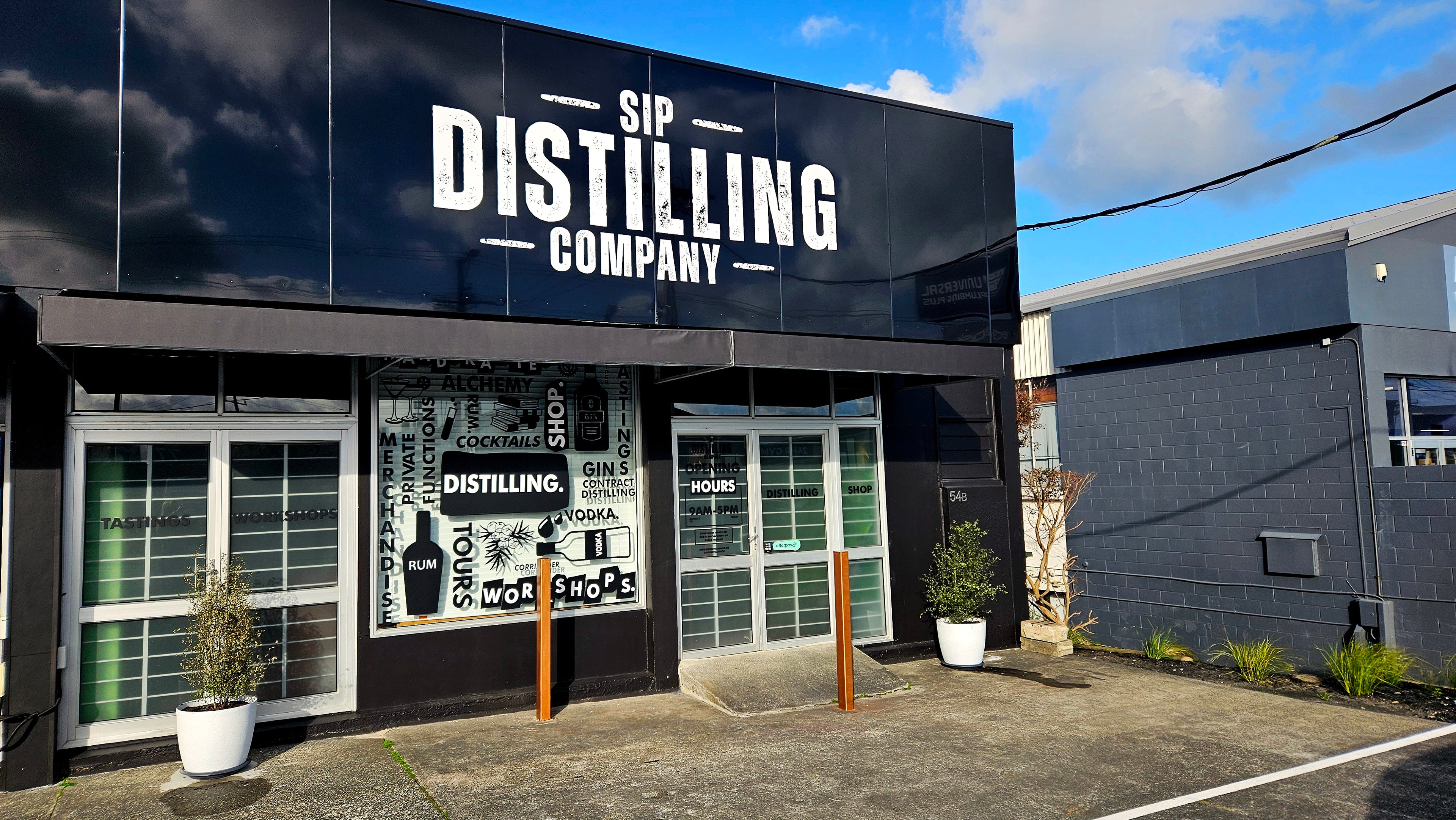 Black building with 'Sip Distilling Company' sign on a clear day