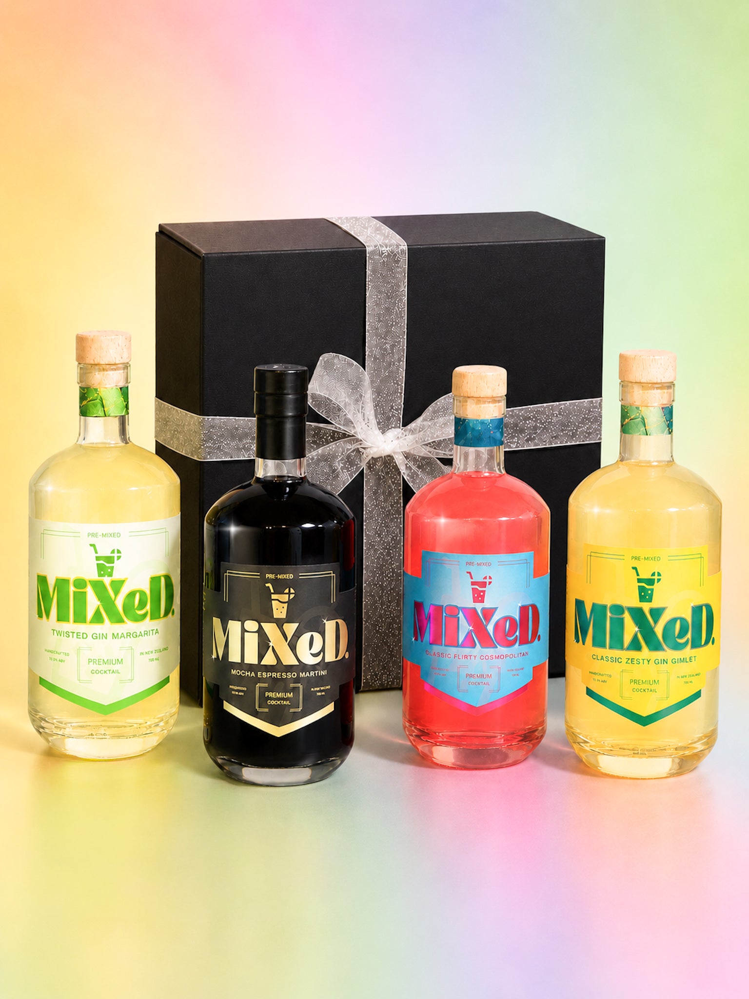 Four bottles of Mixed drinks in front of a black gift box with a white ribbon on a gradient background.