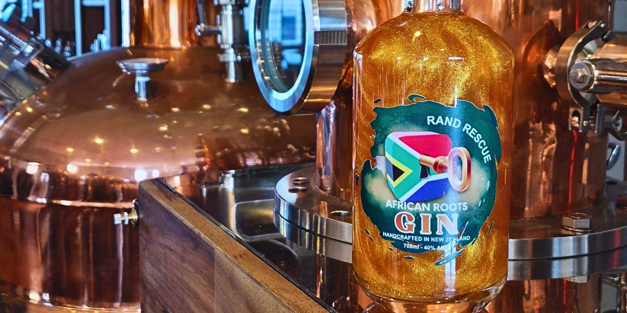 Bottle of Rand Rescue African Roots Gin in front of a copper still